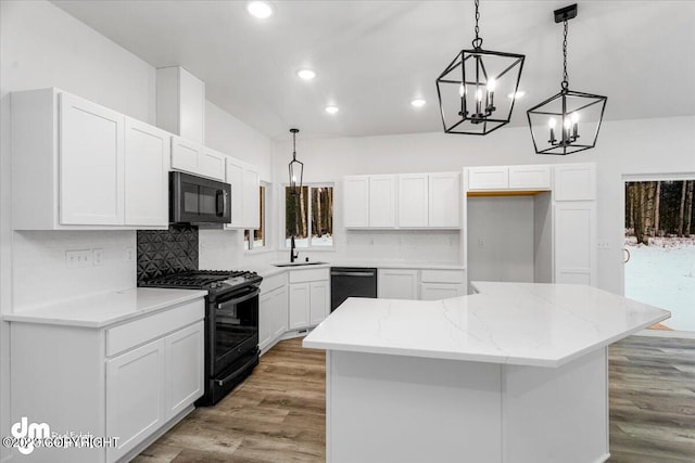 kitchen featuring a sink, black appliances, wood finished floors, and a center island