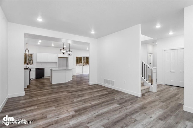 unfurnished living room with visible vents, baseboards, dark wood-style floors, and stairway