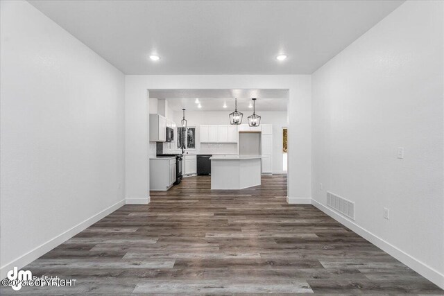 unfurnished living room with dark wood finished floors, visible vents, recessed lighting, and baseboards