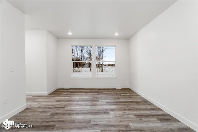 empty room featuring recessed lighting, baseboards, and wood finished floors