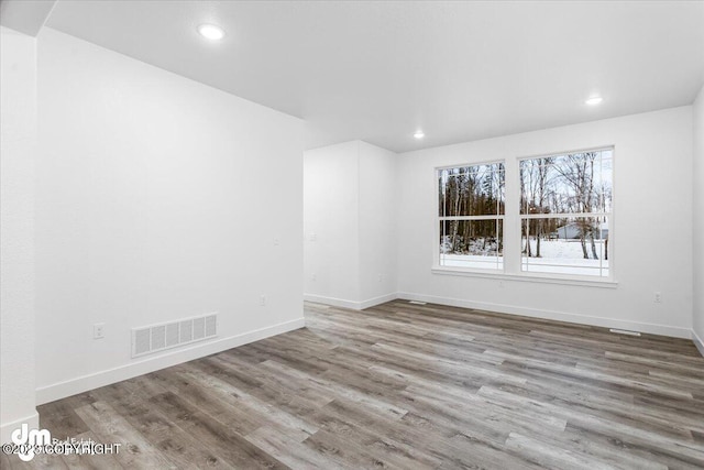 spare room with visible vents, baseboards, and wood finished floors