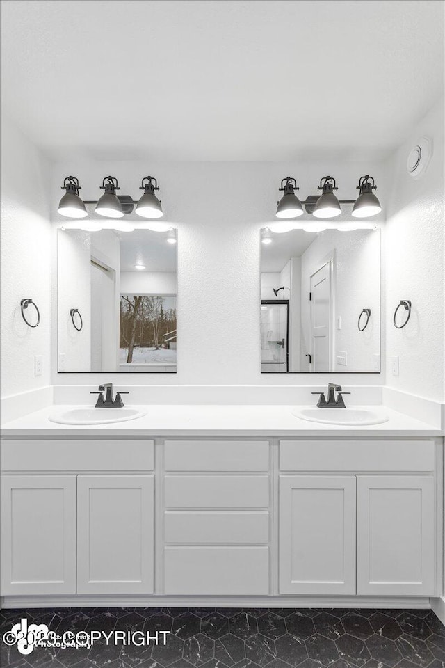 full bathroom with double vanity, a shower, and a sink