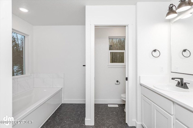 bathroom with tile floors, toilet, a bath, and vanity