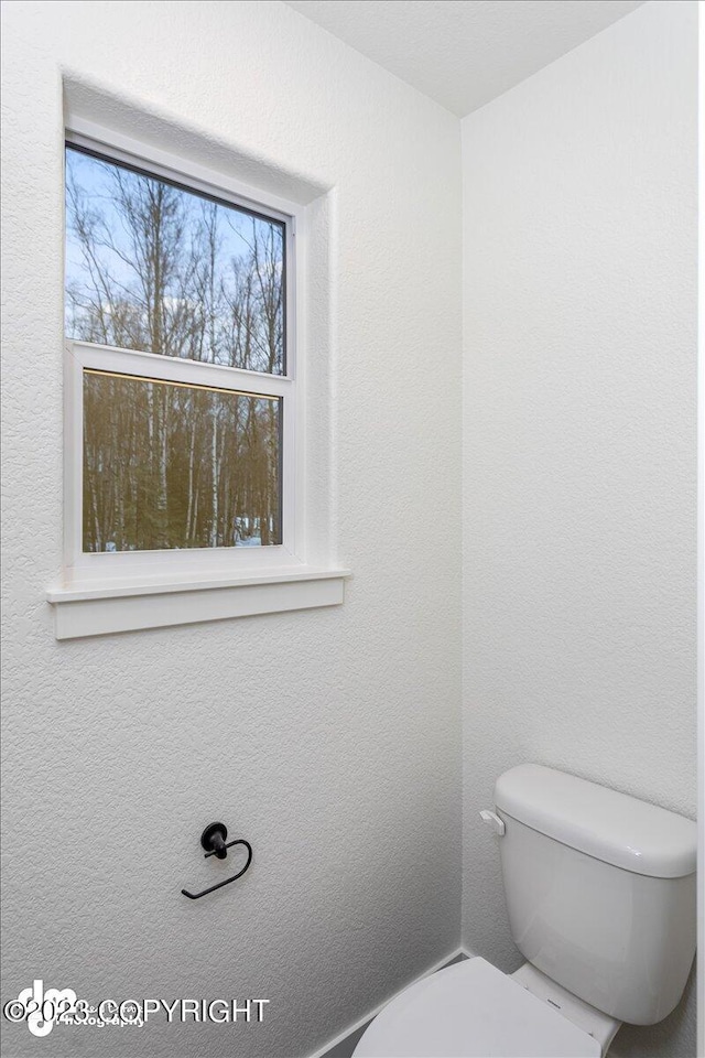 bathroom featuring toilet and a textured wall