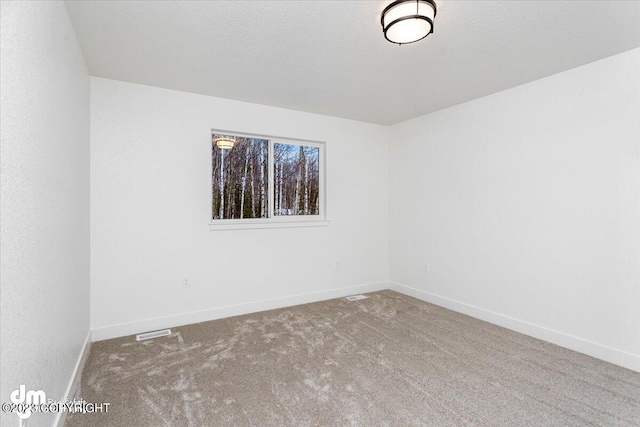 unfurnished room with carpet flooring, a textured ceiling, and baseboards