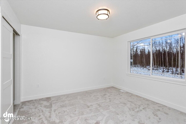 unfurnished bedroom featuring a closet, a textured ceiling, baseboards, and carpet