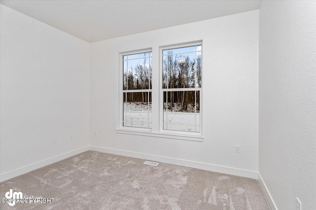 empty room with carpet flooring, visible vents, and baseboards