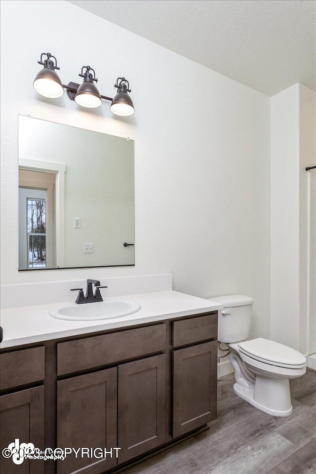 bathroom featuring hardwood / wood-style flooring, vanity, toilet, and a textured ceiling