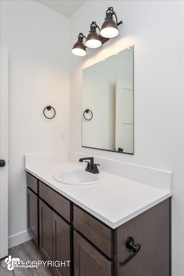 bathroom with baseboards, wood finished floors, and vanity