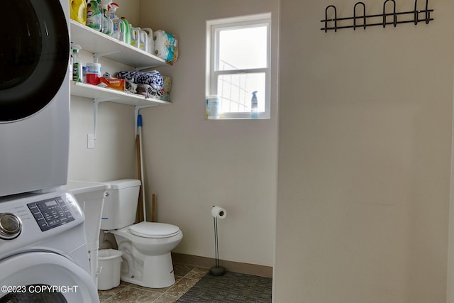 bathroom featuring tile floors, toilet, and stacked washing maching and dryer