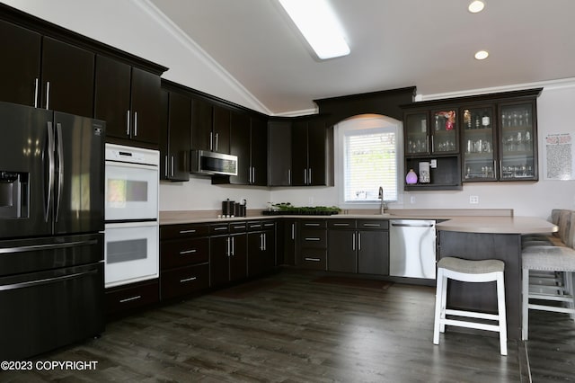 kitchen featuring appliances with stainless steel finishes, vaulted ceiling, a kitchen breakfast bar, ornamental molding, and dark hardwood / wood-style floors