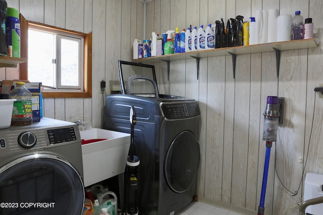 clothes washing area with wooden walls and washing machine and dryer