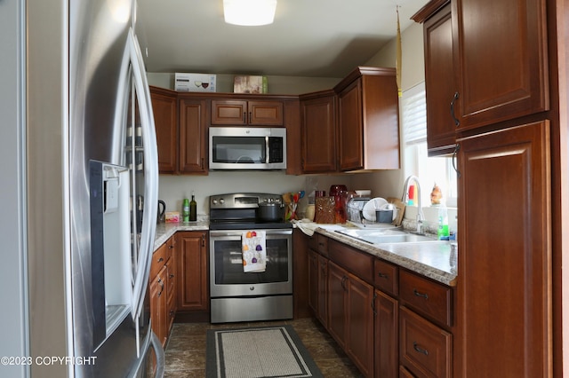 kitchen featuring dark tile floors, appliances with stainless steel finishes, light stone countertops, and sink