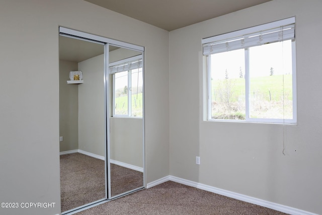 unfurnished bedroom featuring carpet flooring, a closet, and multiple windows