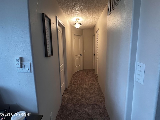 hallway with a textured ceiling and carpet flooring