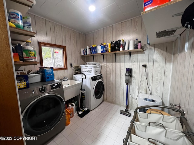 washroom with washing machine and clothes dryer, tile flooring, sink, and wooden walls