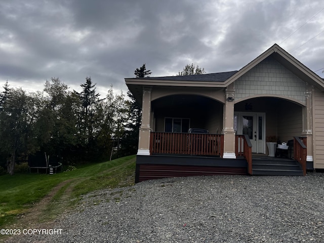 view of front of home with a porch, a front lawn, and french doors