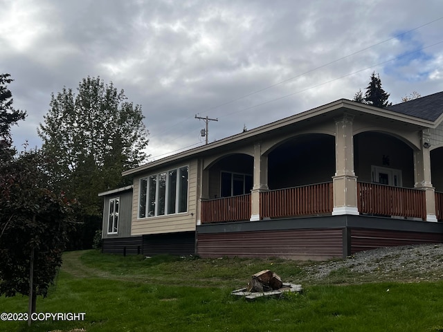 view of side of home featuring a porch and a yard