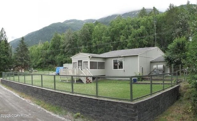 rear view of house featuring a yard, fence private yard, a mountain view, and a view of trees