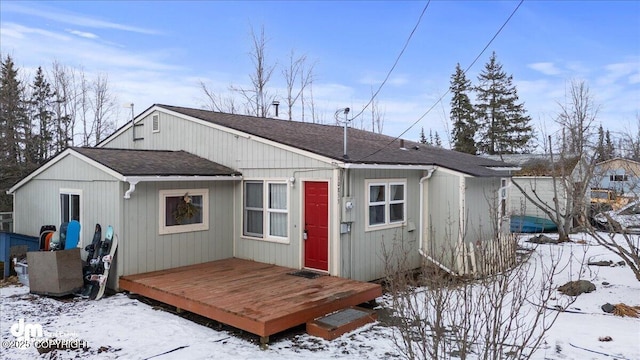 snow covered property featuring a deck and roof with shingles