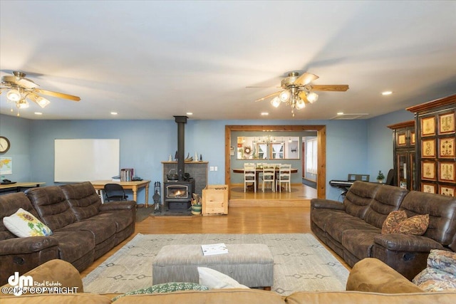 living room with recessed lighting, a wood stove, ceiling fan, and wood finished floors