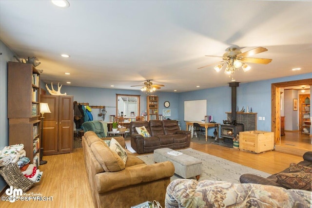 living room featuring recessed lighting, a wood stove, light wood-style flooring, and a ceiling fan