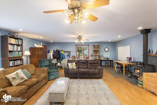 living area with a wood stove, recessed lighting, wood finished floors, and ceiling fan