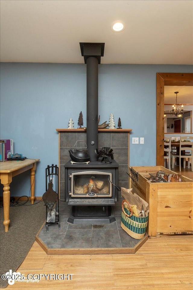 interior details featuring an inviting chandelier, a wood stove, recessed lighting, and wood finished floors