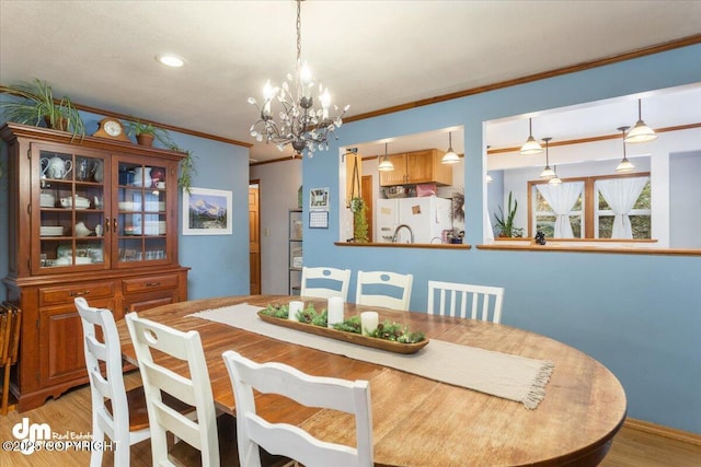 dining room featuring light wood-type flooring, a chandelier, and ornamental molding