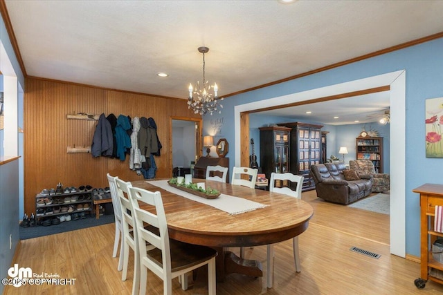 dining room featuring ornamental molding, ceiling fan with notable chandelier, visible vents, and light wood-type flooring