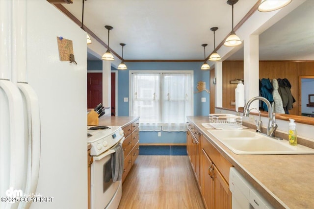 kitchen with crown molding, pendant lighting, light countertops, white appliances, and a sink