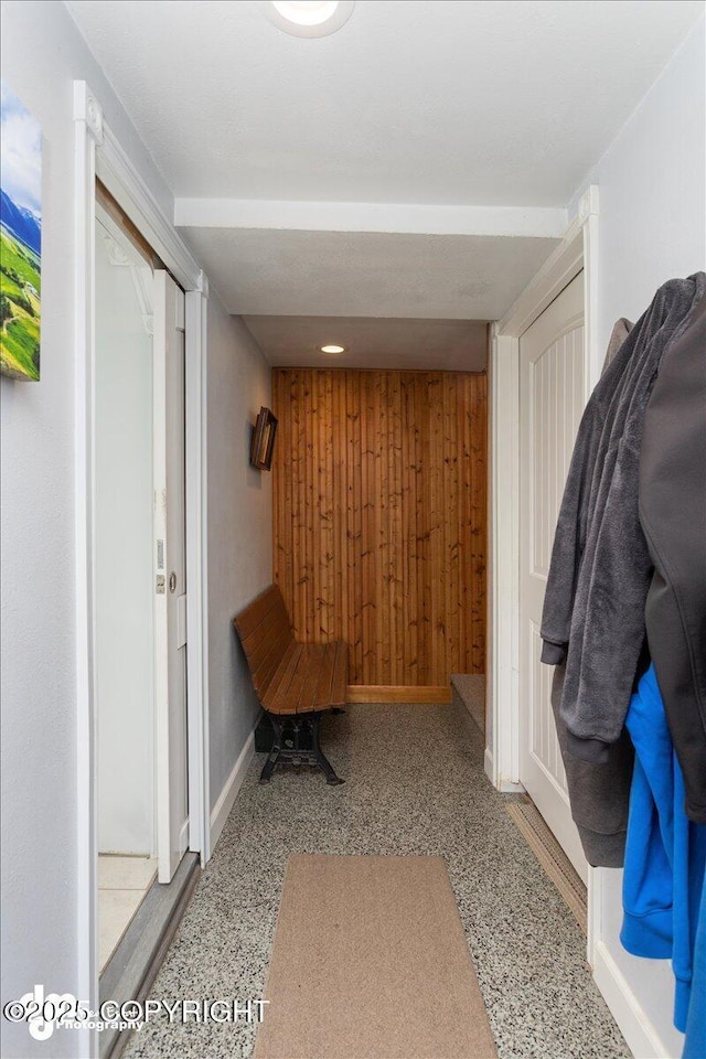 mudroom with wood walls, speckled floor, and baseboards