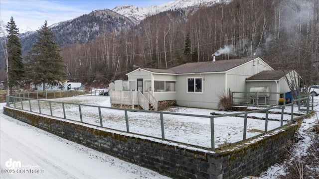 snow covered property featuring a mountain view, a forest view, and fence