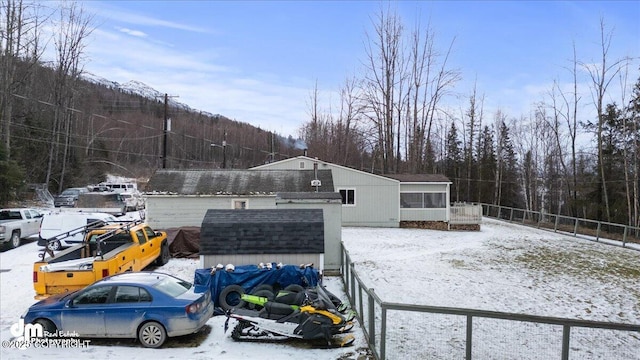 snowy yard with a storage shed, an outdoor structure, and fence