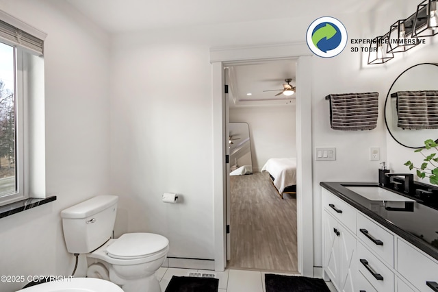 ensuite bathroom with connected bathroom, toilet, vanity, a ceiling fan, and tile patterned floors