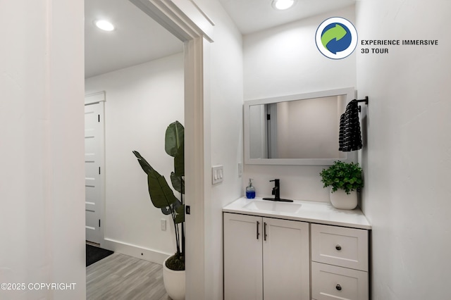 bathroom with recessed lighting, baseboards, wood finished floors, and vanity