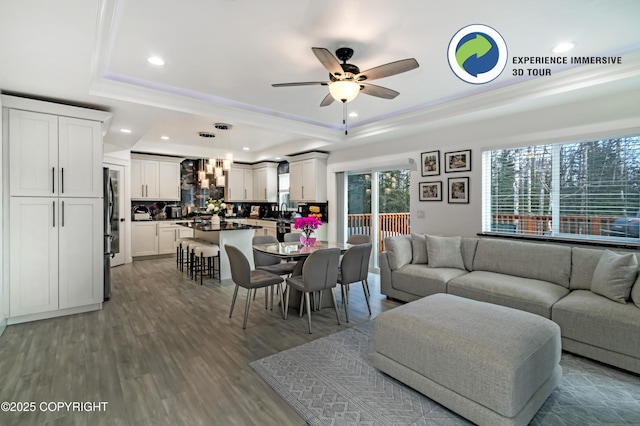 living area featuring ceiling fan, wood finished floors, a raised ceiling, and recessed lighting