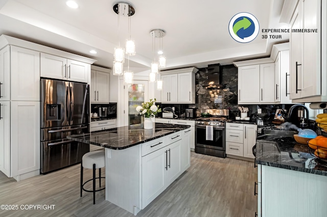 kitchen featuring a sink, refrigerator with ice dispenser, wall chimney range hood, decorative backsplash, and stainless steel gas stove