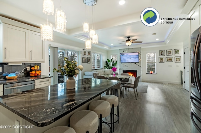 kitchen featuring dark wood-style flooring, a high end fireplace, white cabinets, open floor plan, and a tray ceiling