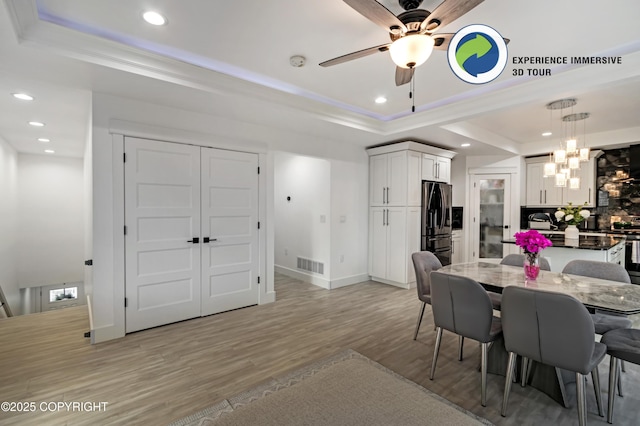 dining space featuring a tray ceiling, recessed lighting, visible vents, light wood-style flooring, and ornamental molding