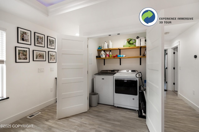 clothes washing area with light wood finished floors, visible vents, washer and dryer, laundry area, and baseboards