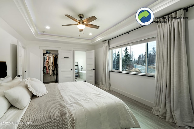 bedroom with baseboards, ornamental molding, wood finished floors, a tray ceiling, and recessed lighting