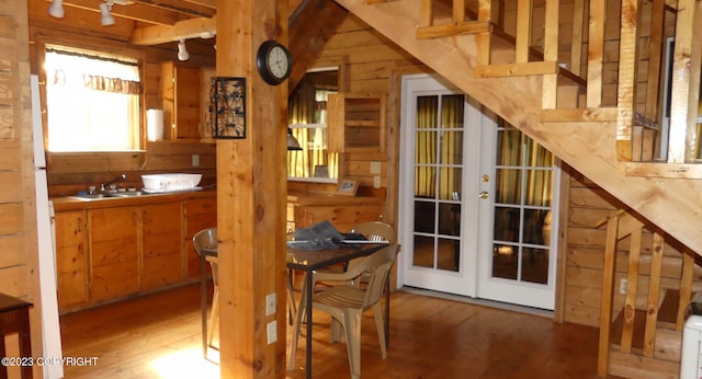 dining area with french doors, sink, hardwood / wood-style flooring, and wood walls