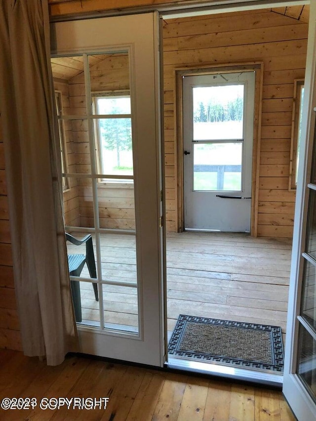 doorway to outside featuring wooden walls and hardwood / wood-style floors