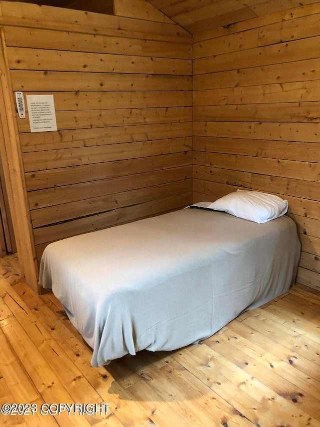 bedroom featuring wooden walls and light hardwood / wood-style floors