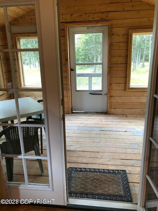 doorway to outside with wood walls