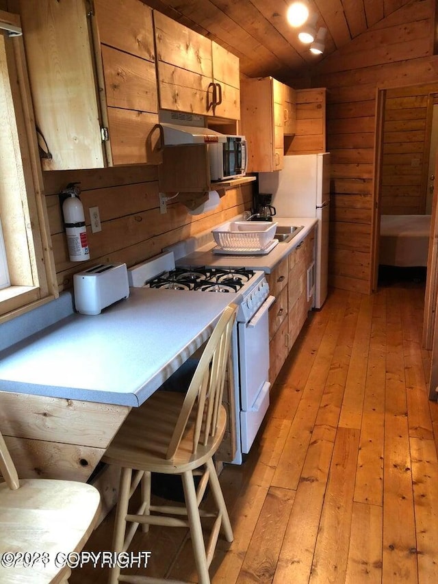 kitchen featuring wood walls, wooden ceiling, vaulted ceiling, light wood-type flooring, and gas range gas stove