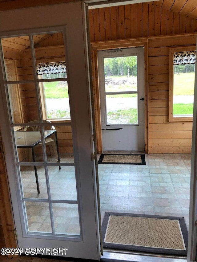 doorway featuring wooden walls and vaulted ceiling