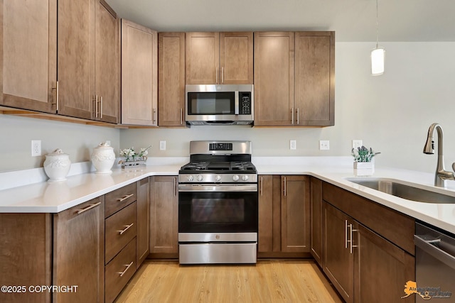 5991 Takotna Loop, Anchorage, AK 99504 - kitchen with appliances with stainless steel finishes, light wood-style flooring, light countertops, and hanging light fixtures