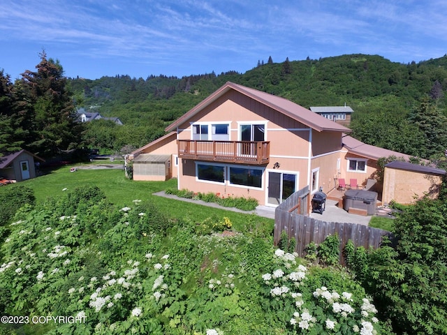 back of property featuring a balcony, a lawn, and outdoor lounge area